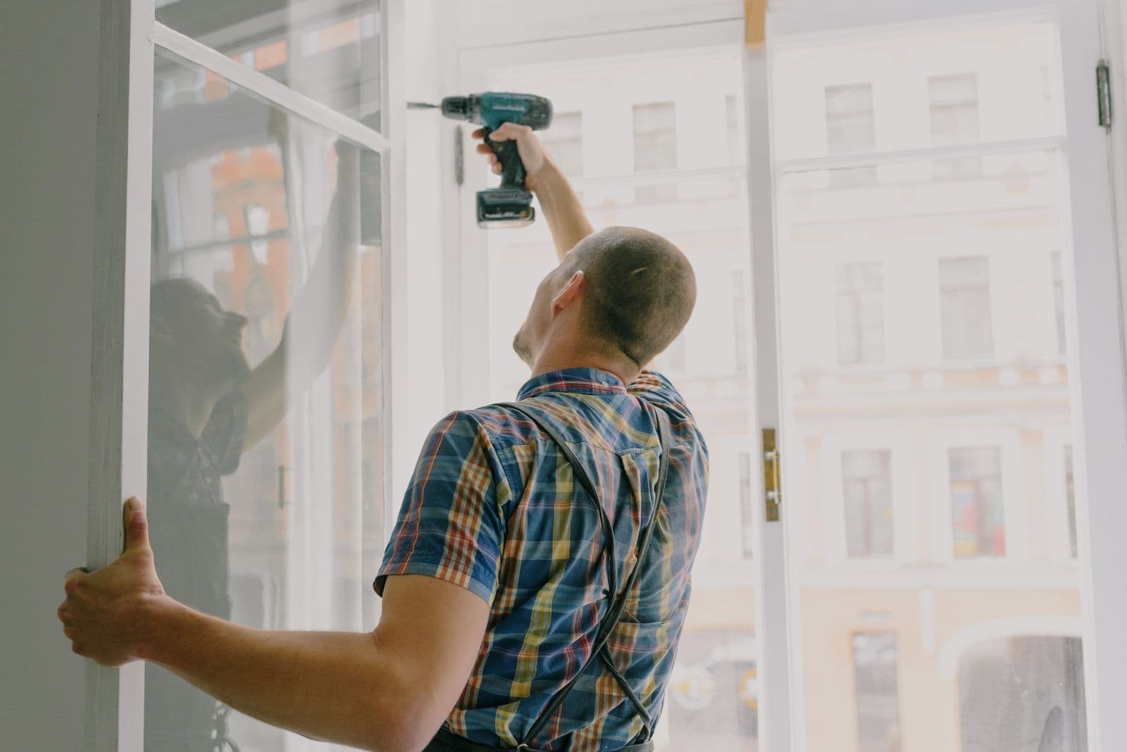 A technician driving a screw with a power drill during an installation