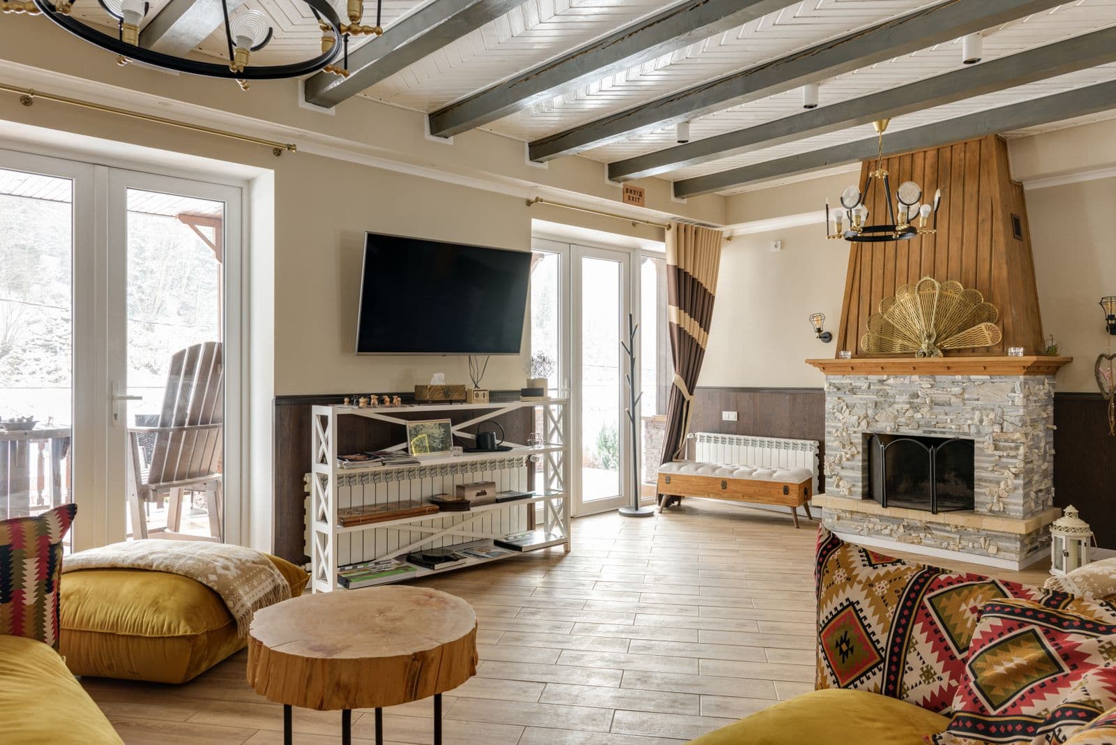 Flat-screen TV mounted flush on the wall of a warm, wood-beamed living room