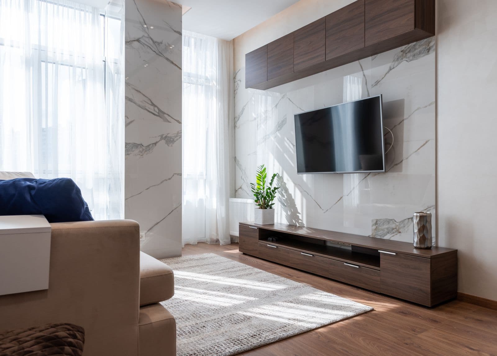A bright living room with wooden furniture and a comfortable couch facing the TV wall
